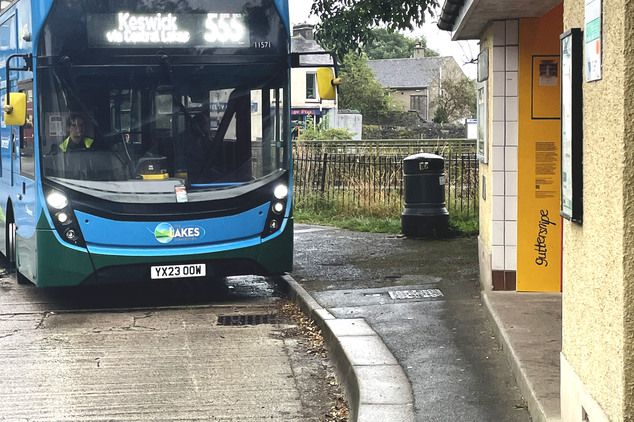 555 bus pulling into bus stop with guttersnipe logo on yellow wall